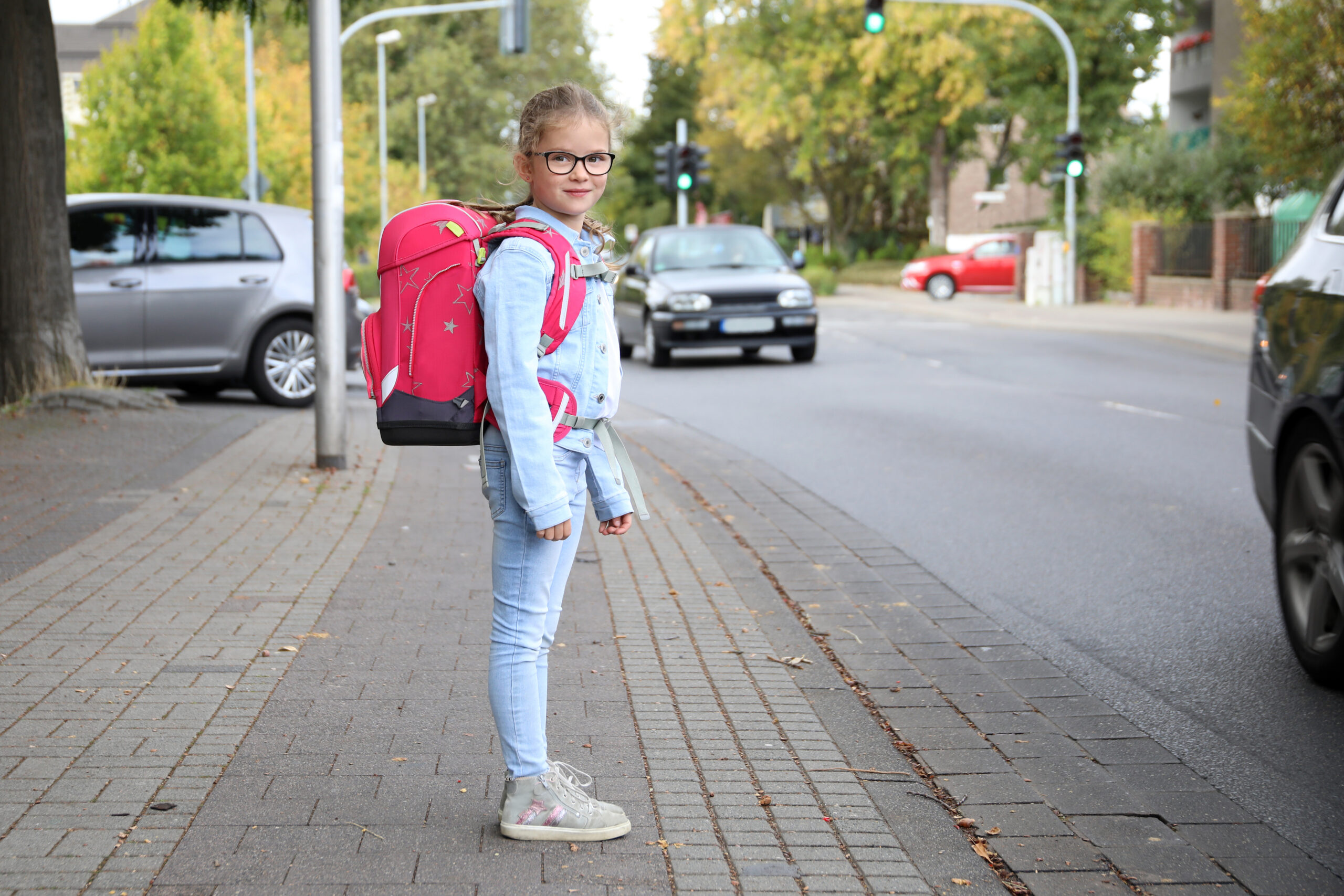 Mädchen mit Schultornister möchte die Strasse überqueren