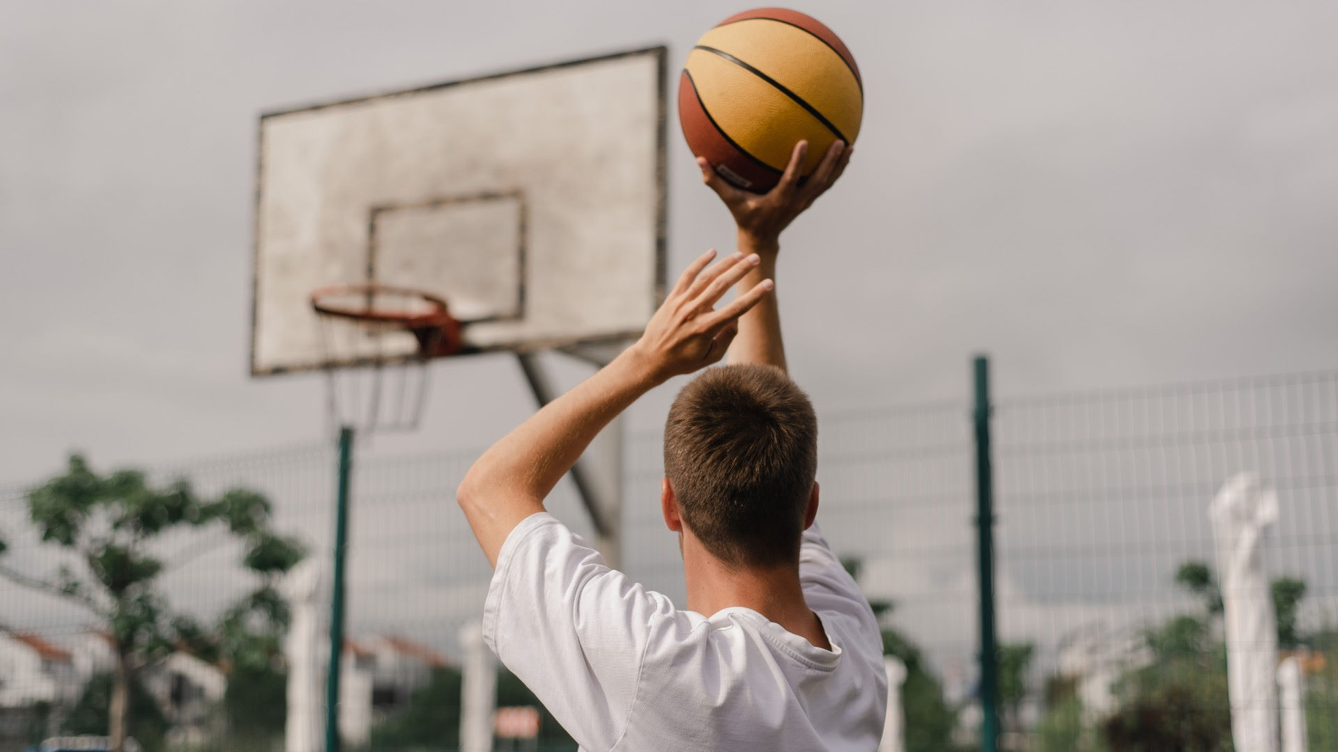 Mann wirft Basketball in den Basketballkorb